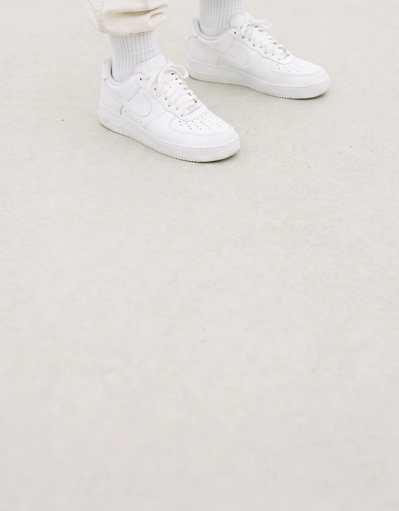 Tenis Air Force 1 blancos puestos, caminando en una cancha de concreto